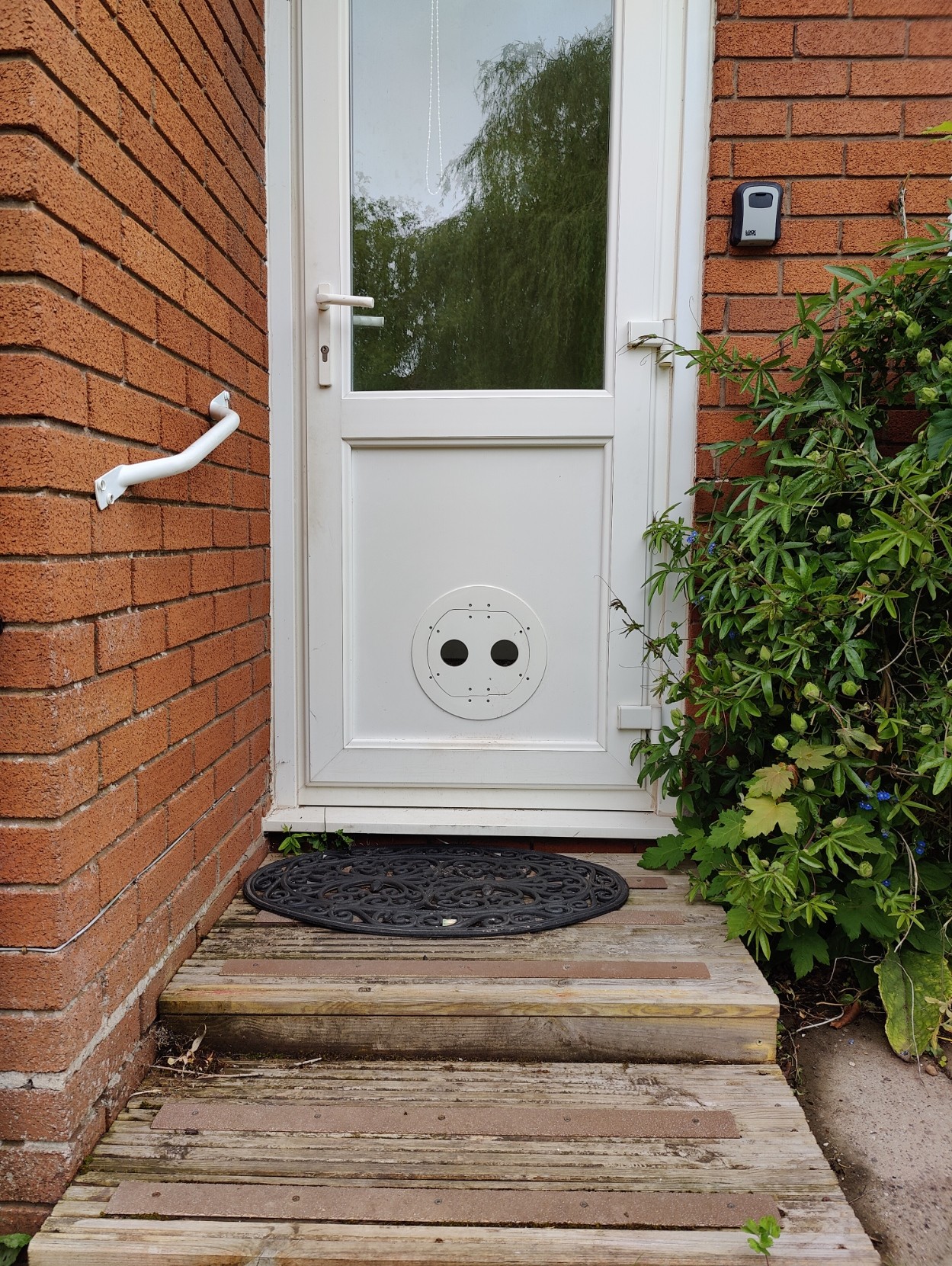 Red brick house with a white back door that has a white Petflap fitted in it.